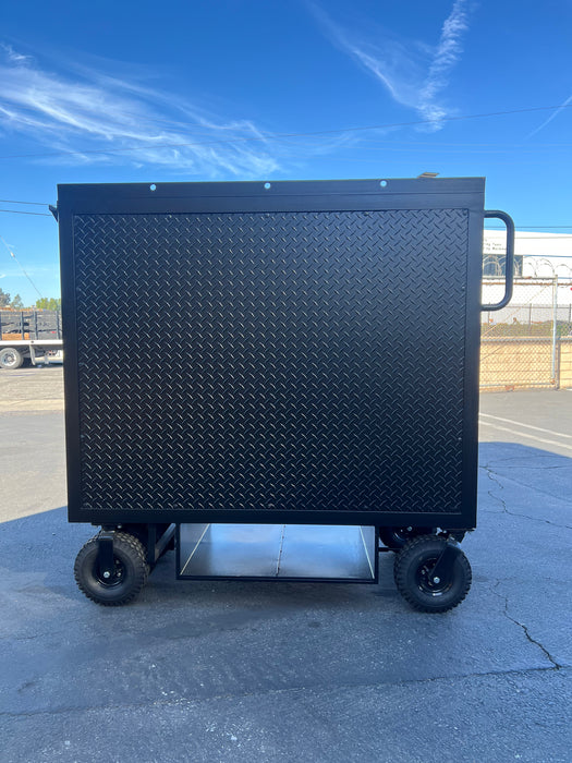 Black metal cart with wheels on a concrete surface under a blue sky.