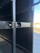 Close-up of a black metal door with a lock mechanism, sunlit outdoor background.
